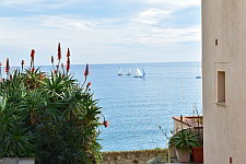 a view of Antibes, from the shore, onto the sea, a few sailing boats